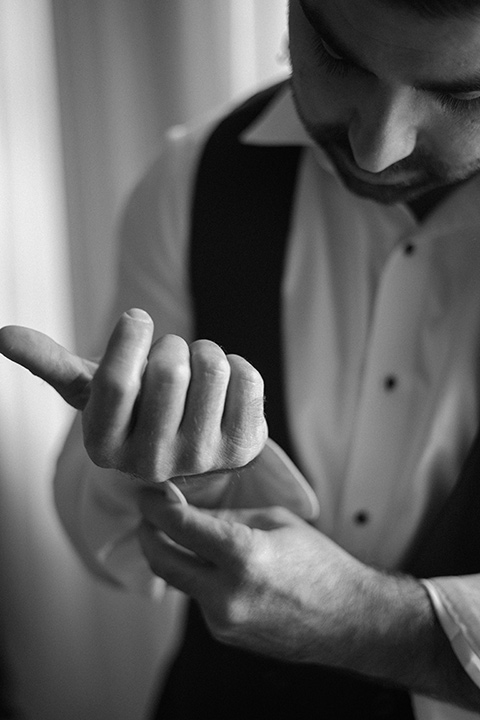  a chic black and white wedding with modern touches with the groom in a white tuxedo and the bride in a white ballgown and the bridesmaids and groomsmen in black dresses/tuxedos – groom getting ready 