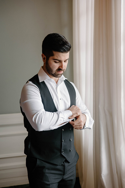  a chic black and white wedding with modern touches with the groom in a white tuxedo and the bride in a white ballgown and the bridesmaids and groomsmen in black dresses/tuxedos – groom getting ready 