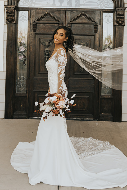  A dreamy amber toned wedding in Arizona at a wedgewood wedding venue – with the bride in a long sleeve lace gown and the bridesmaids in burnt orange dresses and the groom in a café brown suit and the groomsmen in a tan suit – bride in her wedding dress