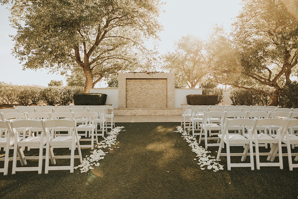 A dreamy amber toned wedding in Arizona at a wedgewood wedding venue – with the bride in a long sleeve lace gown and the bridesmaids in burnt orange dresses and the groom in a café brown suit and the groomsmen in a tan suit – couple at the ceremony