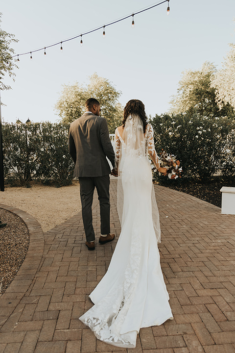  A dreamy amber toned wedding in Arizona at a wedgewood wedding venue – with the bride in a long sleeve lace gown and the bridesmaids in burnt orange dresses and the groom in a café brown suit and the groomsmen in a tan suit – couple cheersing