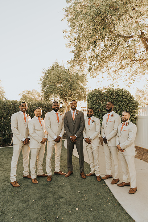  A dreamy amber toned wedding in Arizona at a wedgewood wedding venue – with the bride in a long sleeve lace gown and the bridesmaids in burnt orange dresses and the groom in a café brown suit and the groomsmen in a tan suit – groom and groomsmen