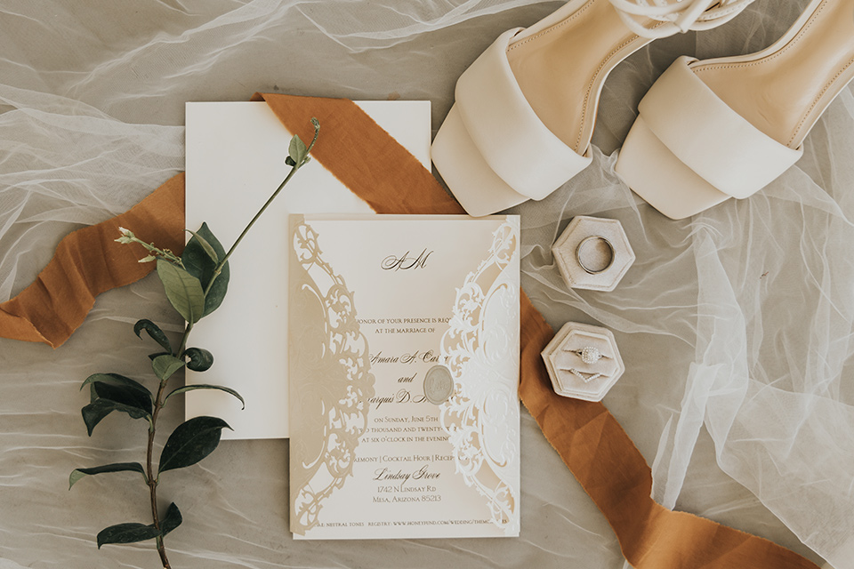 A dreamy amber toned wedding in Arizona at a wedgewood wedding venue – with the bride in a long sleeve lace gown and the bridesmaids in burnt orange dresses and the groom in a café brown suit and the groomsmen in a tan suit – invitations