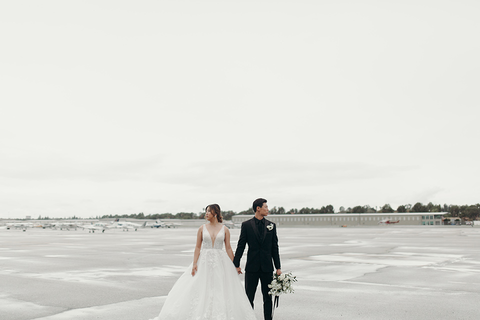  moody dark wedding at with a helicopter venue with the groom in an all-black tuxedo and the bride in a white a-line gown 