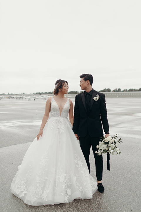  moody dark wedding at with a helicopter venue with the groom in an all-black tuxedo and the bride in a white a-line gown 