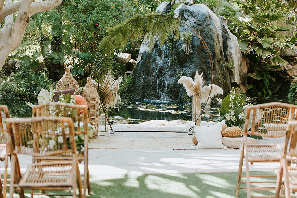  bohemian wedding with the bride in a flowing lace gown and the groom in a caramel brown suit with a green velvet bow tie- ceremony decor