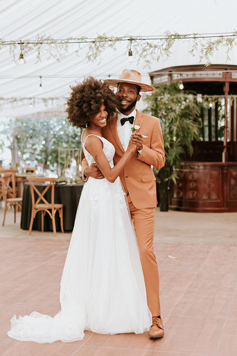  bohemian wedding with the bride in a flowing lace gown and the groom in a caramel brown suit with a green velvet bow tie- couple dancing