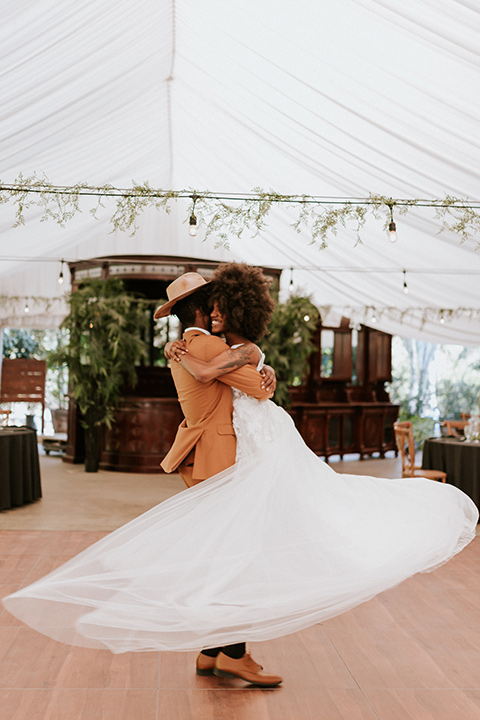  bohemian wedding with the bride in a flowing lace gown and the groom in a caramel brown suit with a green velvet bow tie- couple dancing 