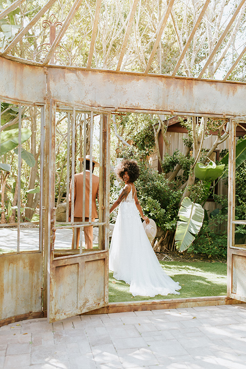  bohemian wedding with the bride in a flowing lace gown and the groom in a caramel brown suit with a green velvet bow tie- couple walking 