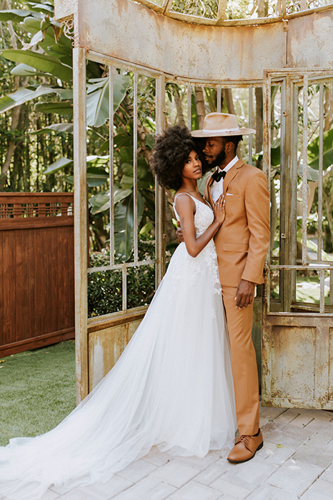  bohemian wedding with the bride in a flowing lace gown and the groom in a caramel brown suit with a green velvet bow tie- couple embracing