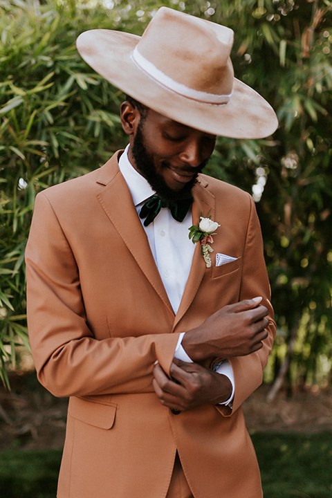  bohemian wedding with the bride in a flowing lace gown and the groom in a caramel brown suit with a green velvet bow tie- groom