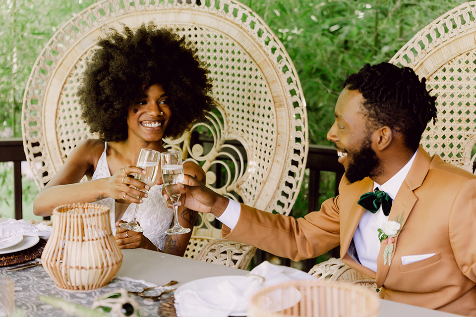  bohemian wedding with the bride in a flowing lace gown and the groom in a caramel brown suit with a green velvet bow tie- couple at sweetheart table