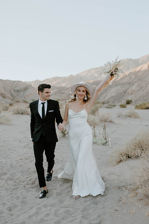  boho wedding in the desert with the groom in a black suit and the bride in a boho bridal gown 