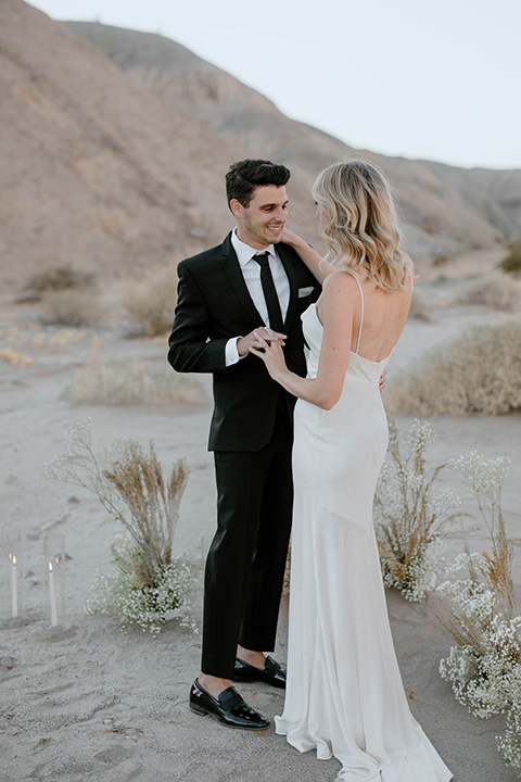  boho wedding in the desert with the groom in a black suit and the bride in a boho bridal gown 