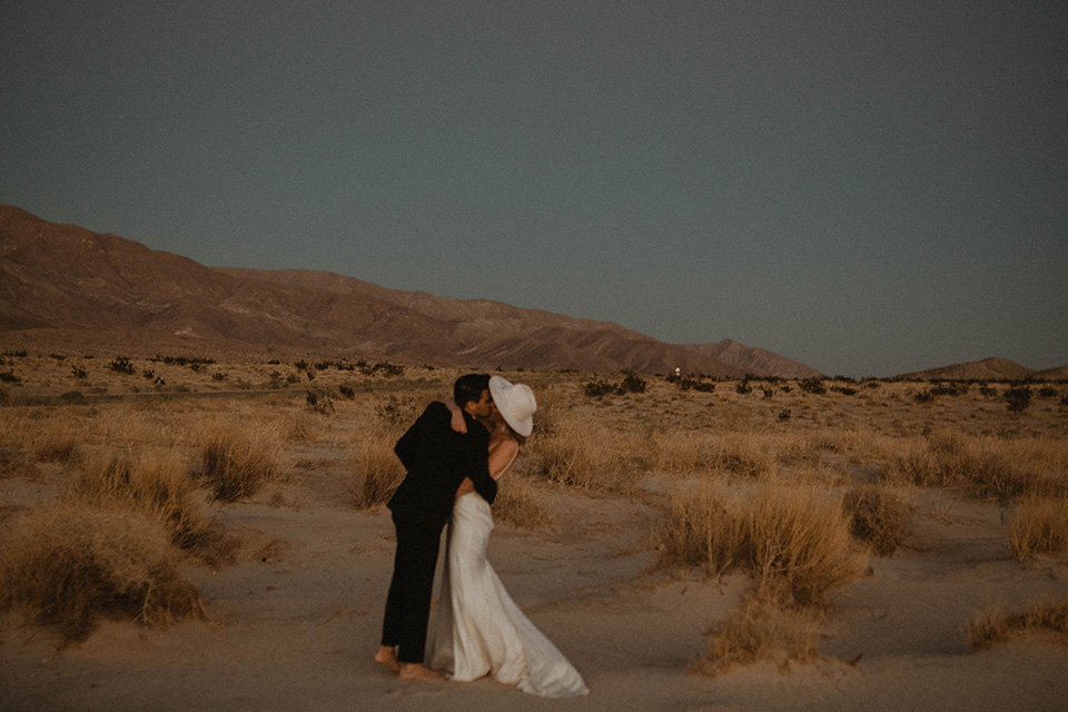  boho wedding in the desert with the groom in a black suit and the bride in a boho bridal gown 