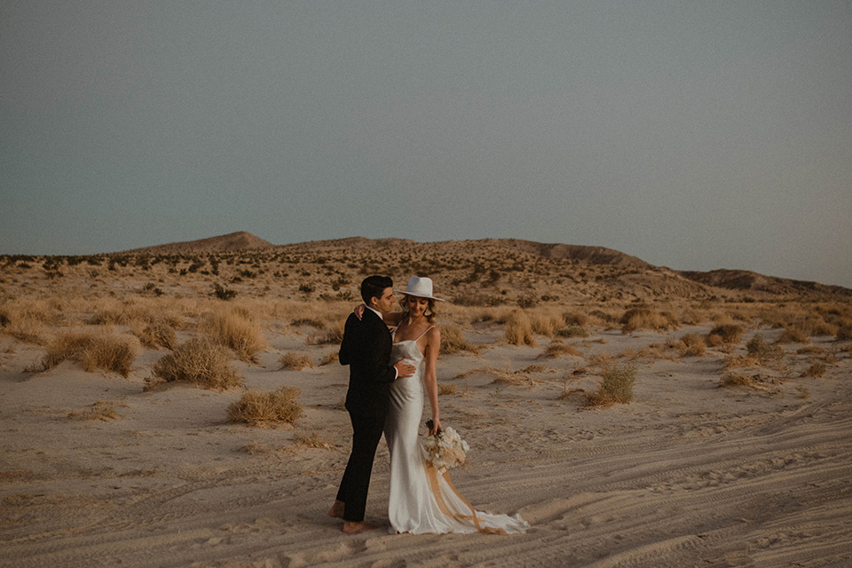  boho wedding in the desert with the groom in a black suit and the bride in a boho bridal gown 