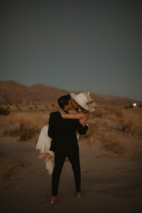  boho wedding in the desert with the groom in a black suit and the bride in a boho bridal gown 