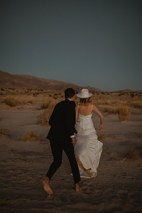  boho wedding in the desert with the groom in a black suit and the bride in a boho bridal gown 