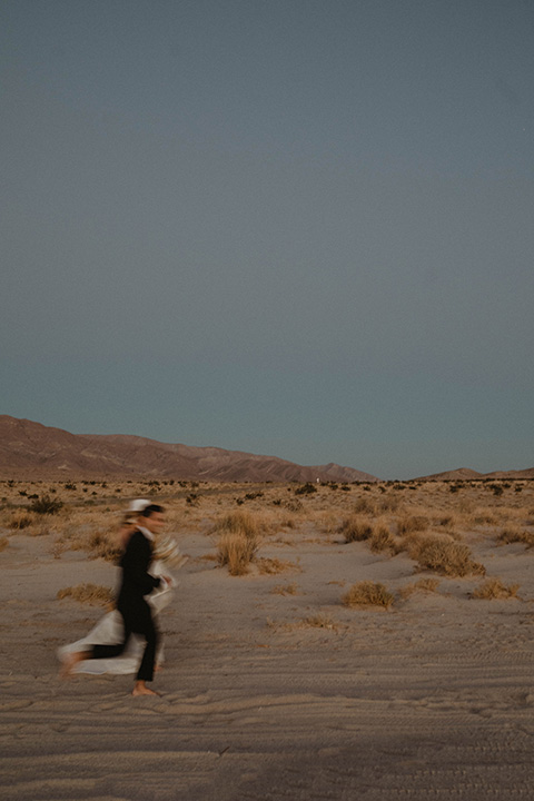  boho wedding in the desert with the groom in a black suit and the bride in a boho bridal gown 