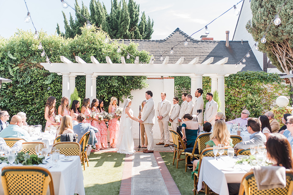  tan and pink garden wedding with floral bridesmaid dresses and the groom and groomsmen in tan suits – ceremony