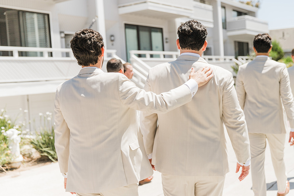  tan and pink garden wedding with floral bridesmaid dresses and the groom and groomsmen in tan suits – groomsmen walking