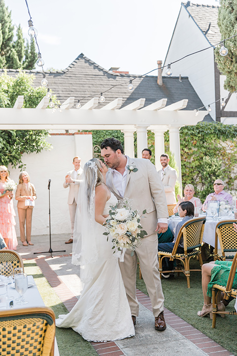  tan and pink garden wedding with floral bridesmaid dresses and the groom and groomsmen in tan suits – kissing at the end of the aisle 