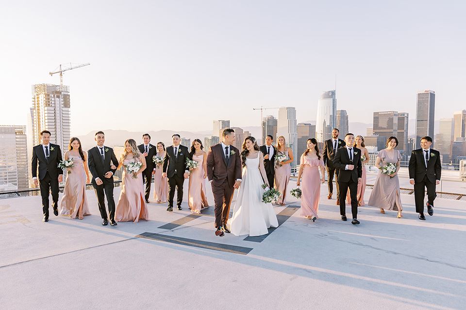 A city wedding with the guys in burgundy and black tuxedos and the bridesmaids in blush dresses- bridalparty walking