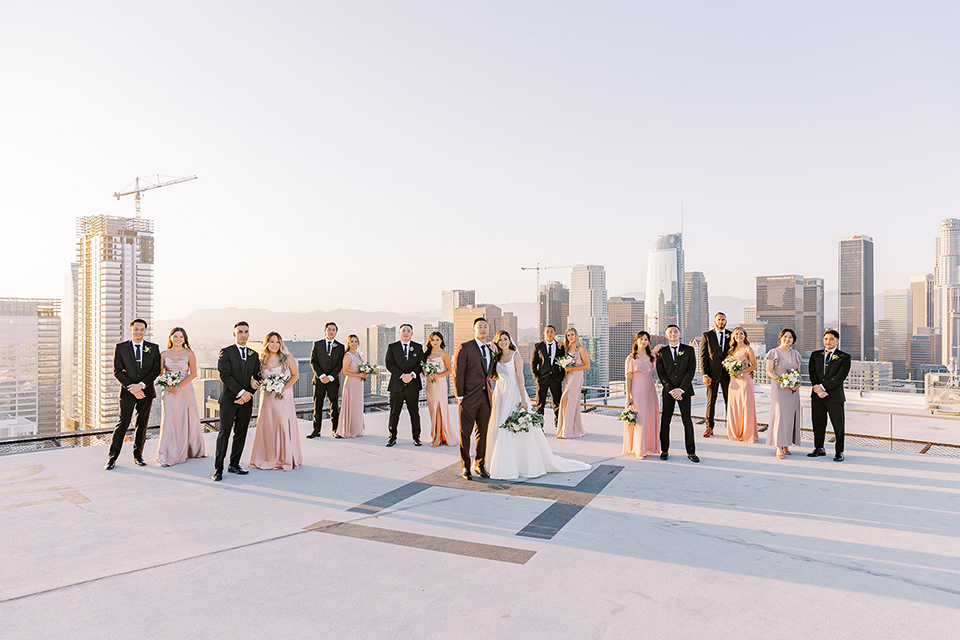 A city wedding with the guys in burgundy and black tuxedos and the bridesmaids in blush dresses- bridalparty walking