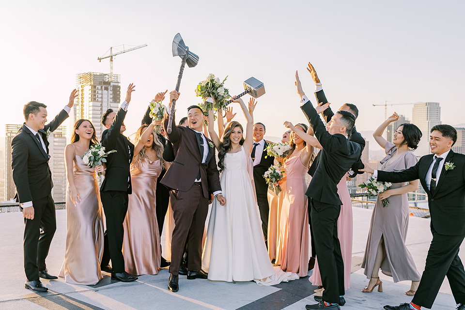 A city wedding with the guys in burgundy and black tuxedos and the bridesmaids in blush dresses- bridalparty cheering