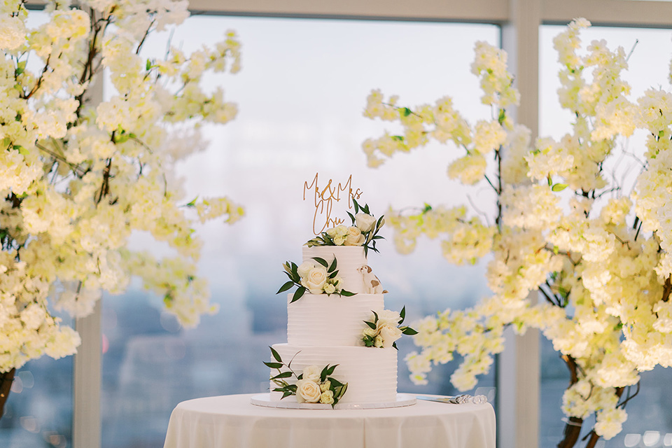 A city wedding with the guys in burgundy and black tuxedos and the bridesmaids in blush dresses- three tiered white cake with flowers