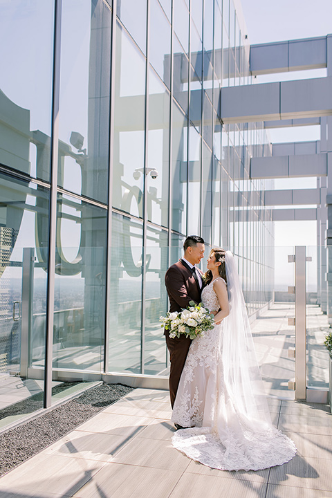  A city wedding with the guys in burgundy and black tuxedos and the bridesmaids in blush dresses- couple by the windows