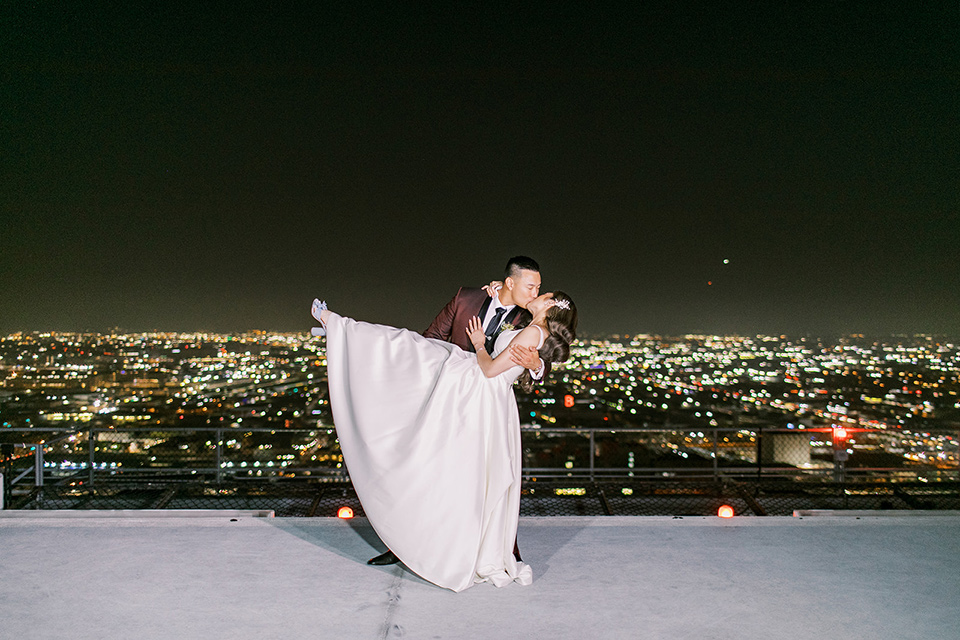 A city wedding with the guys in burgundy and black tuxedos and the bridesmaids in blush dresses- couple on the roof at night