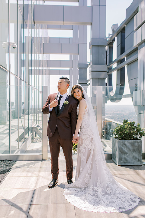  A city wedding with the guys in burgundy and black tuxedos and the bridesmaids in blush dresses- couple by the windows 
