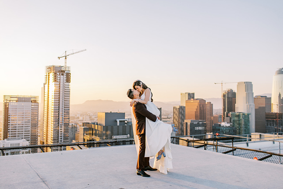 A city wedding with the guys in burgundy and black tuxedos and the bridesmaids in blush dresses- couple on the roof at sunset