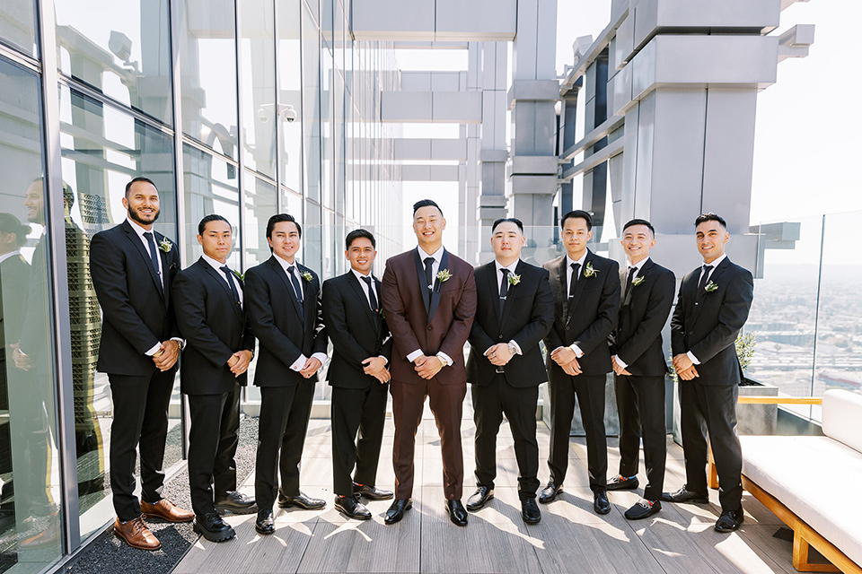 A city wedding with the guys in burgundy and black tuxedos and the bridesmaids in blush dresses- groomsmen