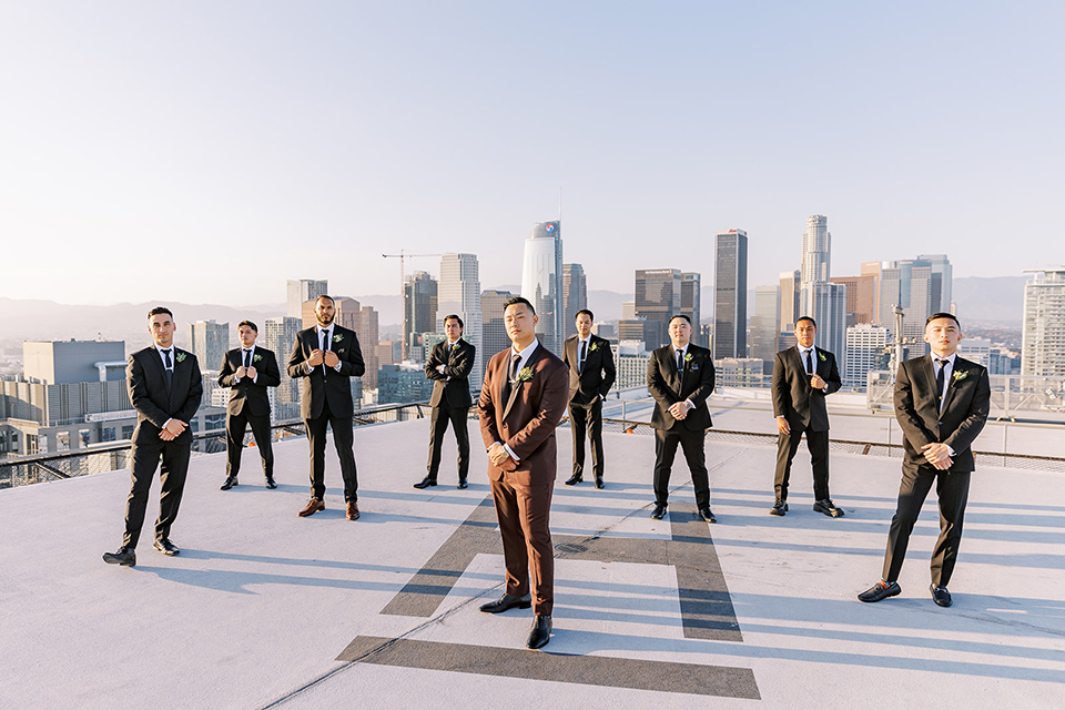 A city wedding with the guys in burgundy and black tuxedos and the bridesmaids in blush dresses- groomsmen on the roof