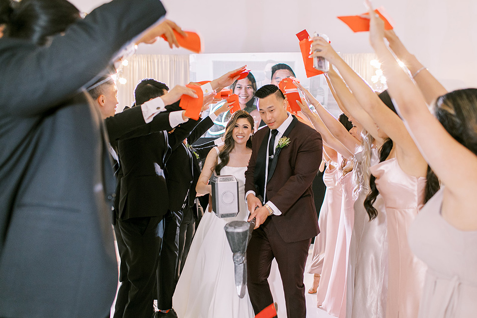 A city wedding with the guys in burgundy and black tuxedos and the bridesmaids in blush dresses- bridalparty cheering