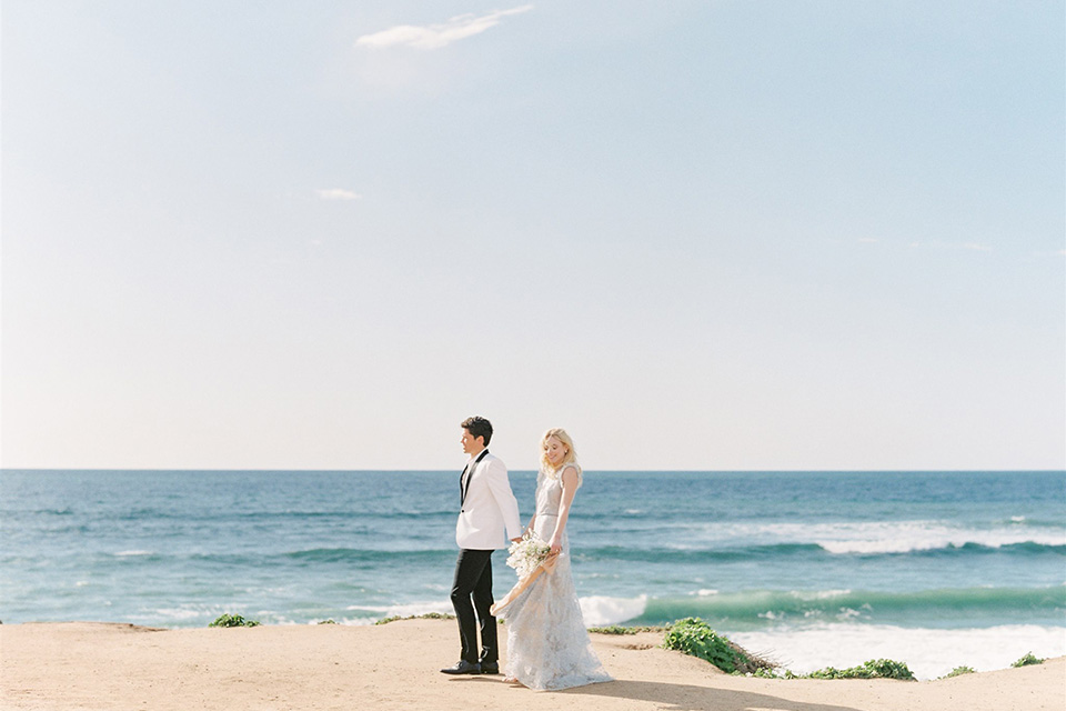  luxe black and white wedding on the beach in san diego – bride in a light blue gown and the groom in a white and black shawl tuxedo 