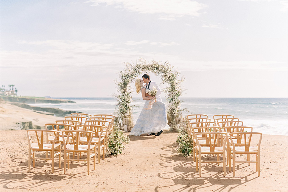  luxe black and white wedding on the beach in san diego – bride in a light blue gown and the groom in a white and black shawl tuxedo 