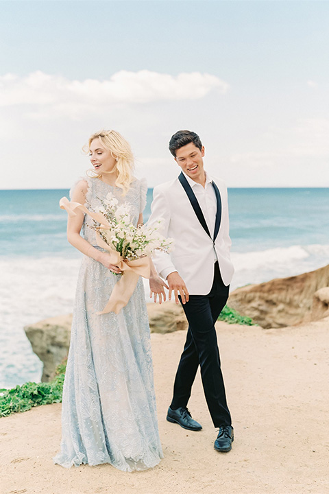  luxe black and white wedding on the beach in san diego – bride in a light blue gown and the groom in a white and black shawl tuxedo