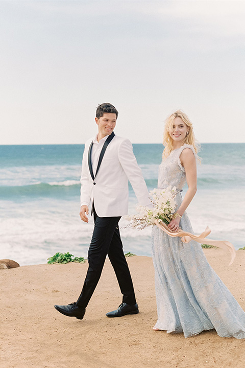  luxe black and white wedding on the beach in san diego – bride in a light blue gown and the groom in a white and black shawl tuxedo 