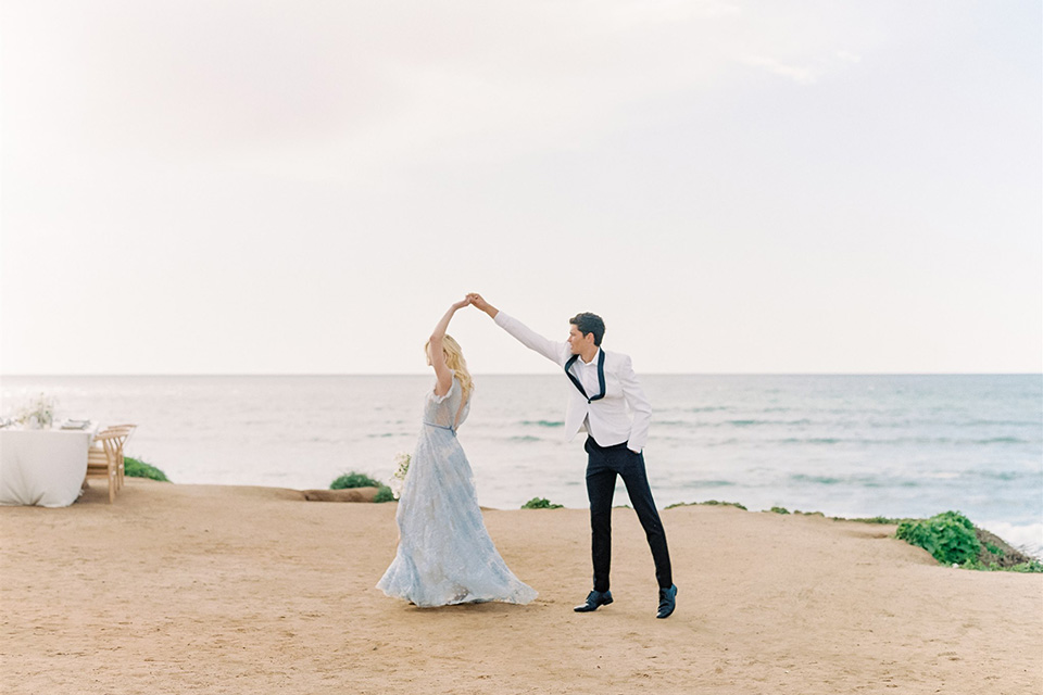  luxe black and white wedding on the beach in san diego – bride in a light blue gown and the groom in a white and black shawl tuxedo 