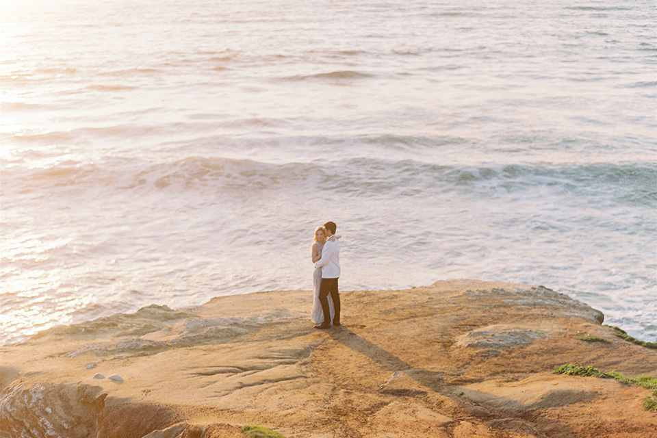  luxe black and white wedding on the beach in san diego – bride in a light blue gown and the groom in a white and black shawl tuxedo 