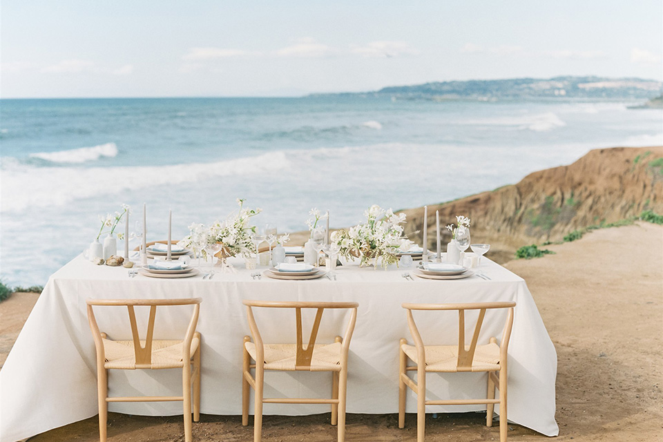  luxe black and white wedding on the beach in san diego – bride in a light blue gown and the groom in a white and black shawl tuxedo 