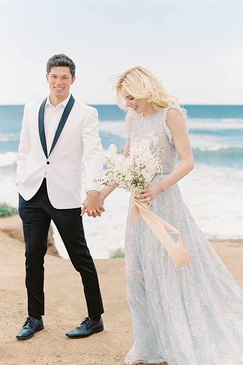  luxe black and white wedding on the beach in san diego – bride in a light blue gown and the groom in a white and black shawl tuxedo 