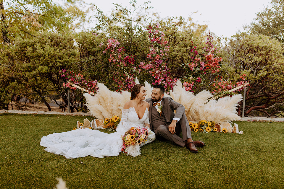  rustic bohemian wedding with brown and gold color scheme – couple sitting in front of pampas grass 