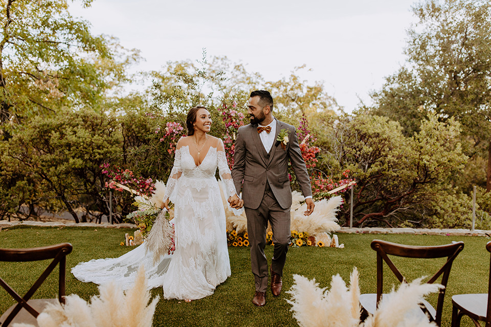  rustic bohemian wedding with brown and gold color scheme – couple walking down the aisle 