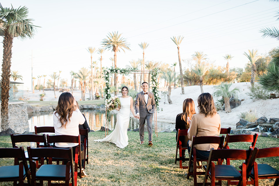  bride in a European inspired gown with lace details, a high neckline, and long sleeves and the groom in a black tuxedo and a black bow tie 