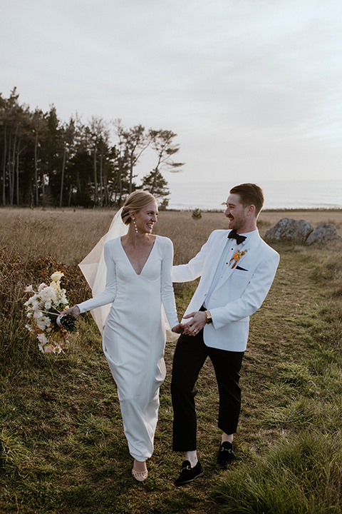  how to change out your groom style look from ceremony to reception with a chic coat swap.  This groom shows off his fun style change by wearing an all-white coat with black pants and then changes into a gold velvet coat for the reception