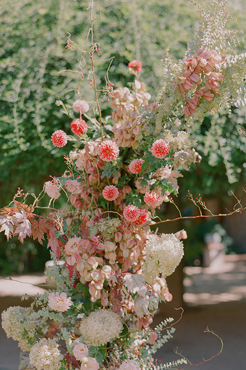  romantic wedding at colony 29 with the bride in a tulle ballgown with sleeves and the groom in a diamond black tuxedo – rose floral arch  